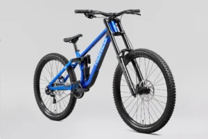 Norco Torrent DH A1 2027 bleu, vue de trois quarts avant : cadre aluminium bleu métallisé, fourche à double té noire, amortisseur arrière et roues mulet (grande roue à l’avant, plus petite à l’arrière), sur fond gris clair.