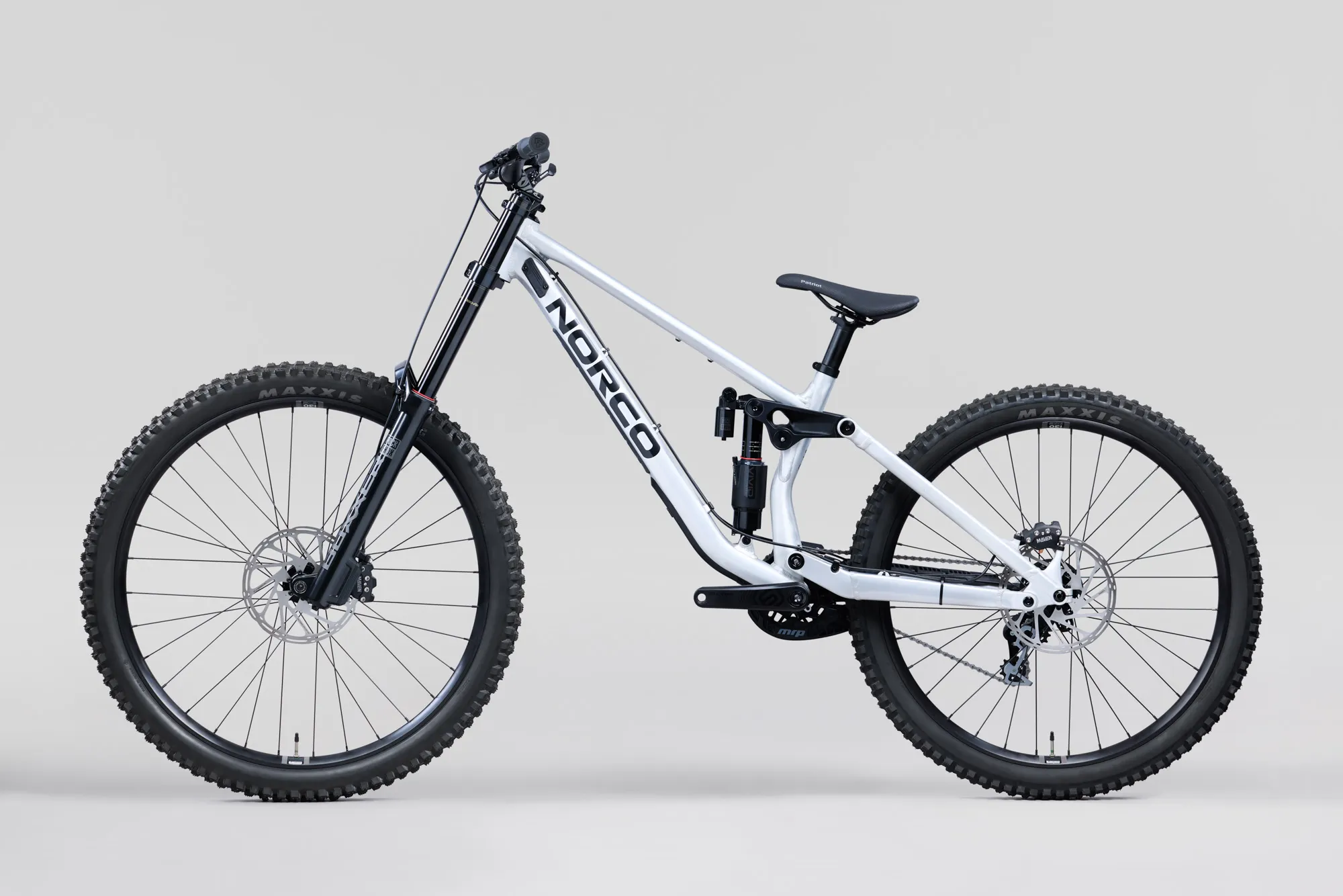 Norco Torrent DH A1 2027 aluminium brut, vue de profil, roue avant à gauche : cadre gris argenté avec logo Norco noir, fourche noire à double té, amortisseur arrière vertical, grande roue avant et roue arrière plus petite.