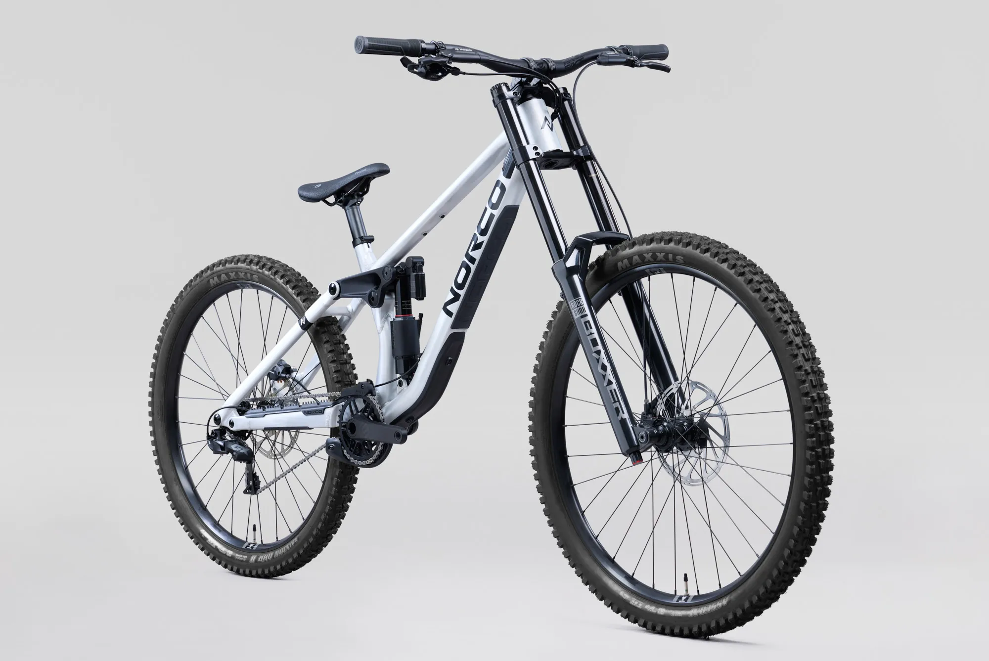 Norco Torrent DH A1 2027 aluminium brut, vue de trois quarts avant : cadre argenté et noir, fourche noire à double té, roues mulet et selle noire, sur fond gris clair.